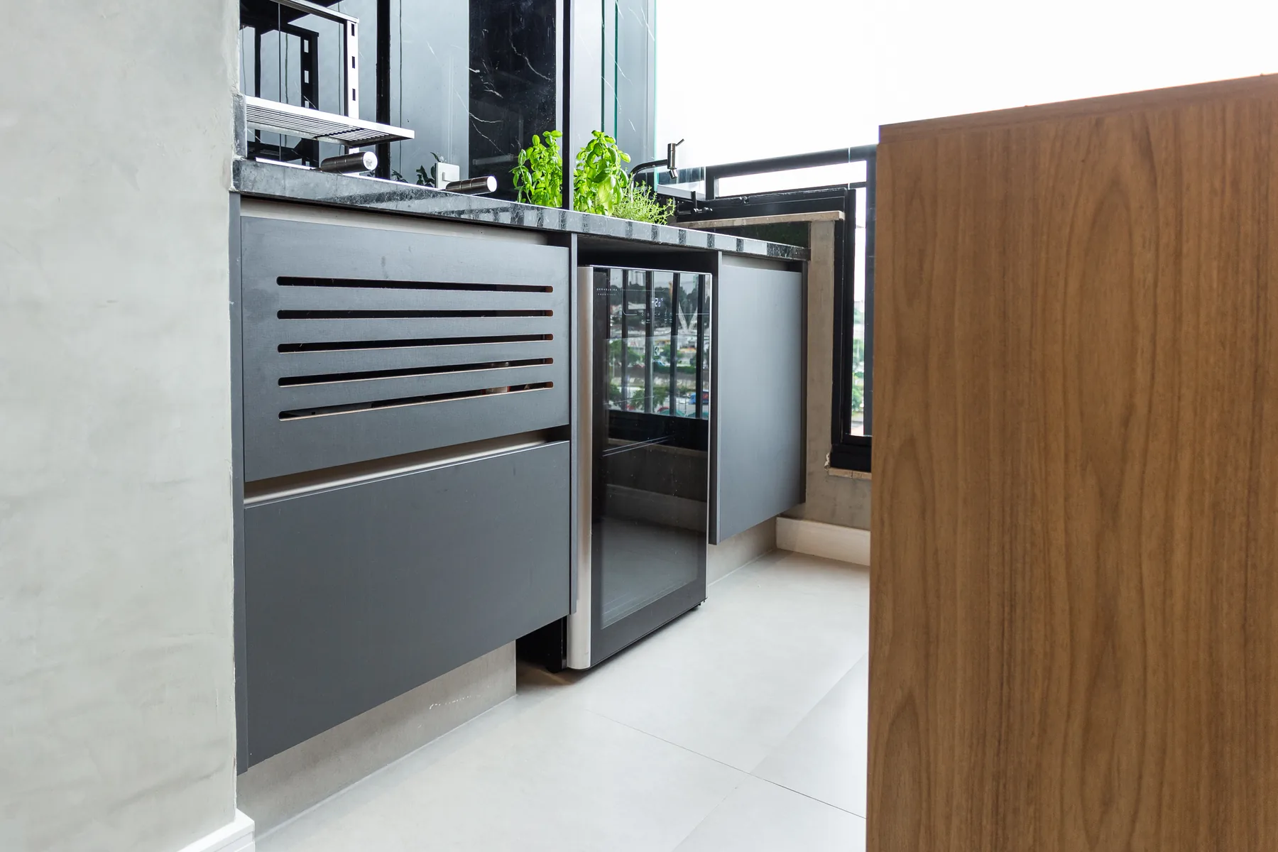 Área gourmet planejada com adega climatizada, frigobar embutido e bancada em granito preto, projeto Linear em São Paulo