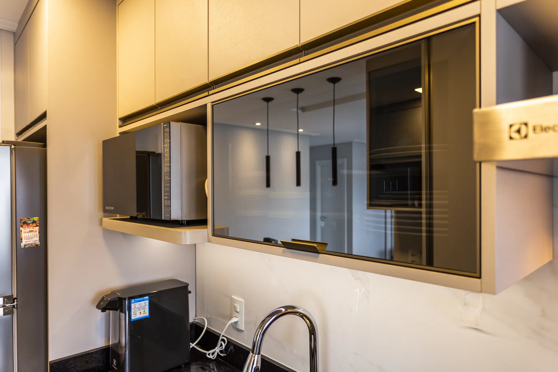 Detalhe de armário aéreo basculante com vidro fumê e perfil metálico em cozinha planejada, projeto Linear em Diadema