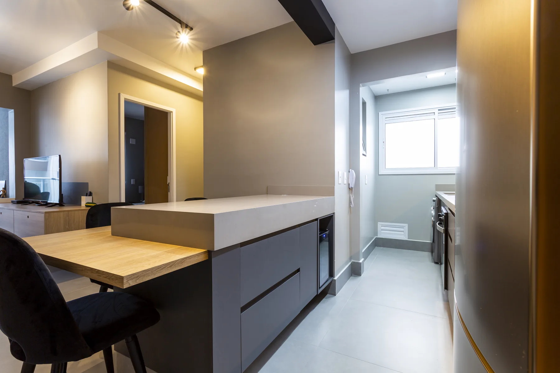 Cozinha planejada compacta com bancada integrada e acesso à lavanderia, projeto Linear em São Paulo