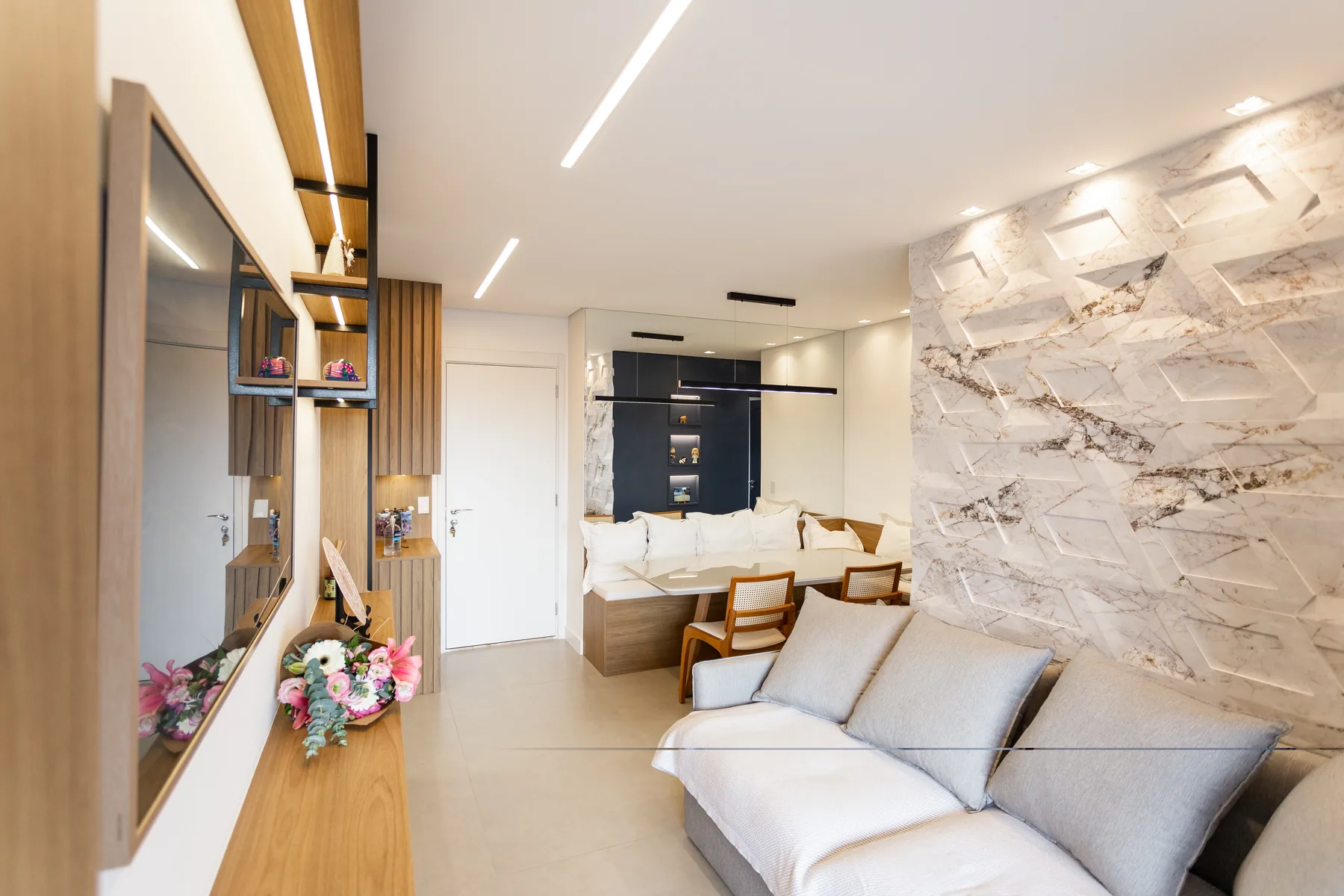 Sala de estar planejada com hall de entrada, espelho e parede revestida em mármore iluminado, projeto Linear em São Paulo
