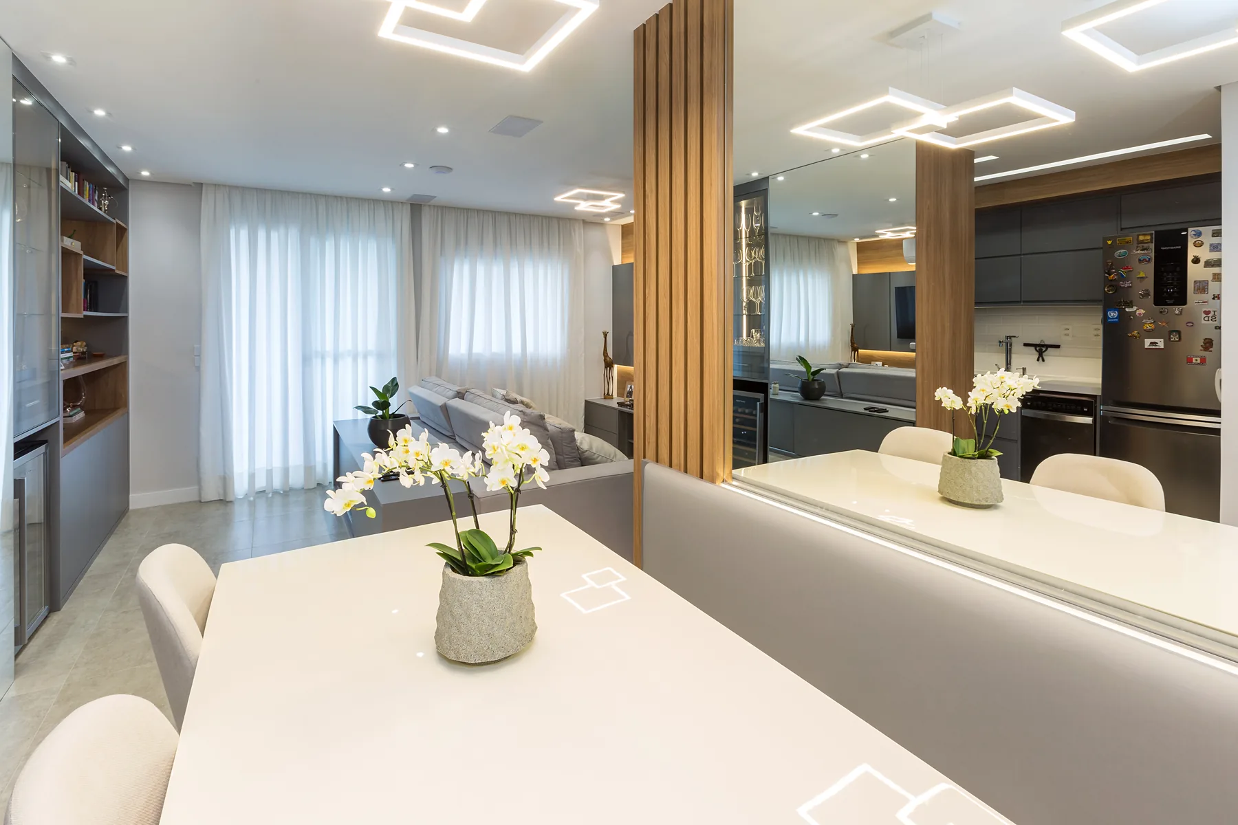 Sala de jantar planejada com mesa, espelho e painel ripado ampliando o ambiente, projeto Linear em Santo André