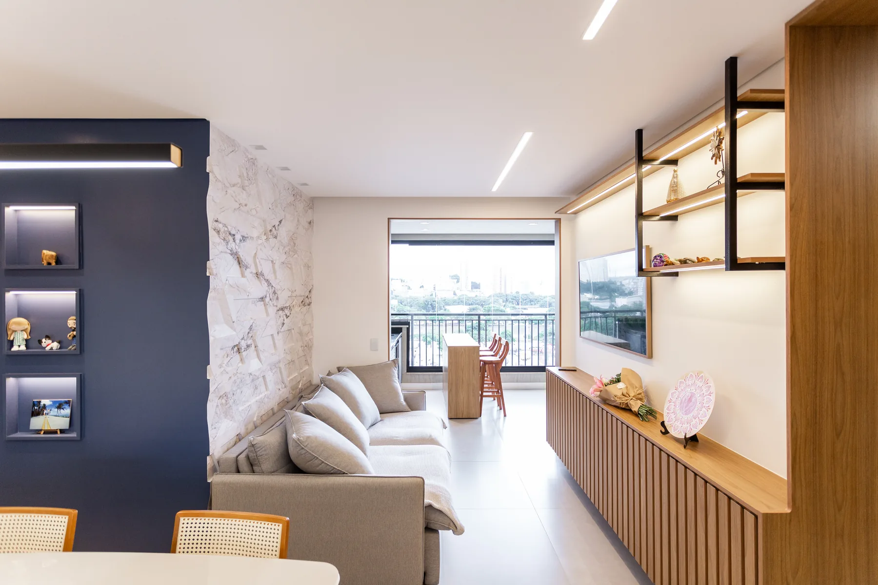 Sala planejada integrada de apartamento com parede em mármore e nichos embutidos, projeto Linear em São Paulo